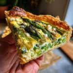Amazing Spring Baking Recipes: 1 Tart 11 A slice of asparagus tart, perfect for Spring Baking Recipes, held in a hand.
