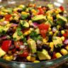 Close-up of a vibrant Avocado Corn Black Bean Salad in a glass bowl, showcasing fresh ingredients.