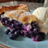 A slice of delicious Blueberry Galette with fresh blueberries and a scoop of vanilla cream.