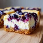 Close-up of a slice of Blueberry Lemon Cheesecake Bars with fresh blueberries.