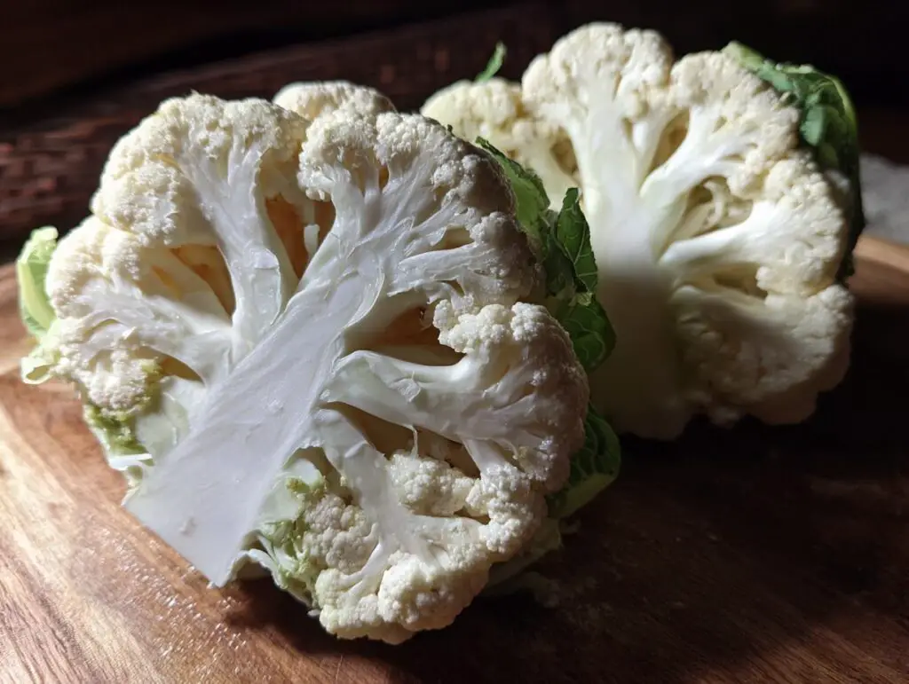 Close-up of a fresh cauliflower head cut in half, ready to make Cauliflower Steaks.