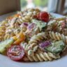 Close-up of chicken pasta salad with creamy greek yogurt dressing, tomatoes, cucumbers, and red onion.