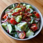 Close-up of a Classic Cucumber Ranch Crack Salad with bacon, tomatoes, and red onion.