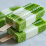 Close-up of two stacked Coconut Lime Popsicles with a green and white striped pattern.