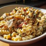 Amazing pasta salad and chicken: 30 min 11 Close-up of creamy pasta salad and chicken in a white bowl, garnished with herbs.