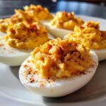 Close-up of creamy queso deviled eggs on a plate, sprinkled with paprika. A delicious appetizer.