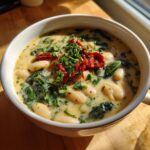 Close-up of a bowl of Creamy Tuscan White Bean Soup with spinach, sun-dried tomatoes, and herbs.