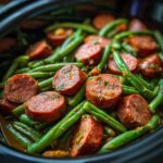 Close-up of cooked Crockpot Kielbasa and Green Beans in a slow cooker, showing sausage and green beans.