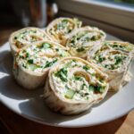 Close-up of Cucumber Dill Cream Cheese Pinwheels on a white plate, showing the filling and fresh ingredients.