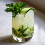 A tall glass of a refreshing Cucumber Mint Gin Cocktail, garnished with fresh mint and cucumber.