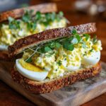 Close-up of a delicious egg salad sandwich with fresh herbs on seeded bread. The egg salad sandwich.