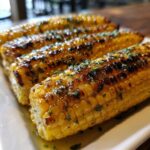 Close-up of grilled corn on the cob with garlic herb butter, a delicious summer side dish.
