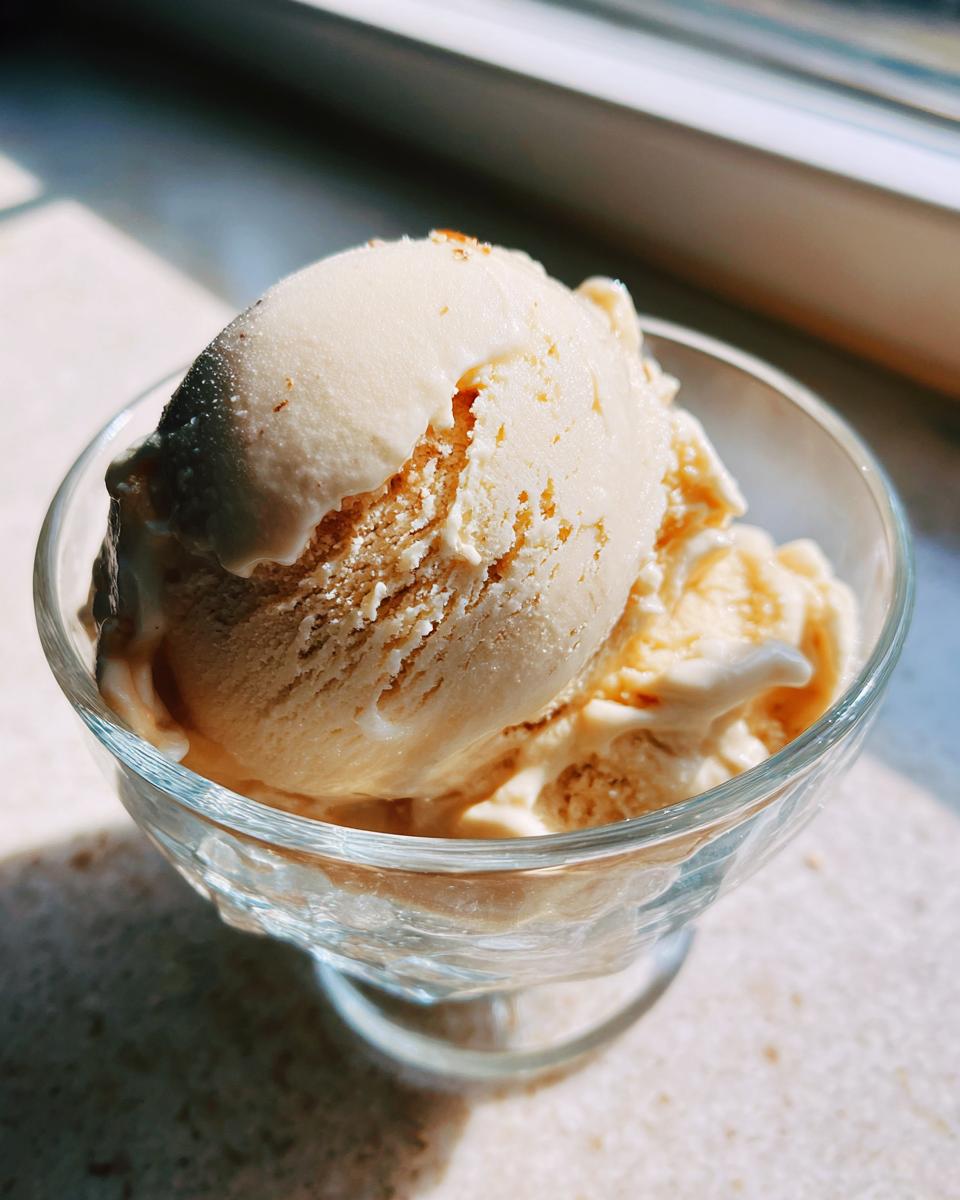 Close-up of scoops of Honey Lavender Ice Cream in a clear glass dessert bowl, bathed in sunlight.