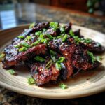 Close-up of Korean BBQ Beef Short Ribs, garnished with green onions and sesame seeds, on a plate.