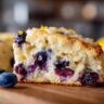 Close-up of a delicious Lemon Blueberry Scone slice with fresh blueberries and lemon zest.
