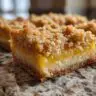 Close-up of a delicious Lemon Crumb Bar with a crumb topping, perfect for dessert.