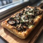 Overhead shot of a Mushroom & Gruyere Tart on a wooden board, ready to eat.