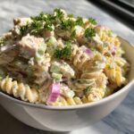 Amazing pasta salad and chicken: 30 min 11 Close-up of a creamy pasta salad and chicken in a white bowl, garnished with parsley. The pasta salad and chicken is a delicious and easy meal.