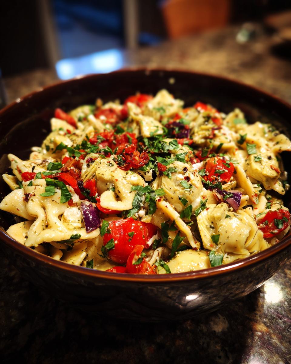Amazing pasta salad artichoke: 1 zesty recipe 7 Close-up of a bowl of pasta salad artichoke with tomatoes, herbs, and red onion.