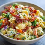 Close-up of a bowl of pasta salad bacon with vegetables and crispy bacon.