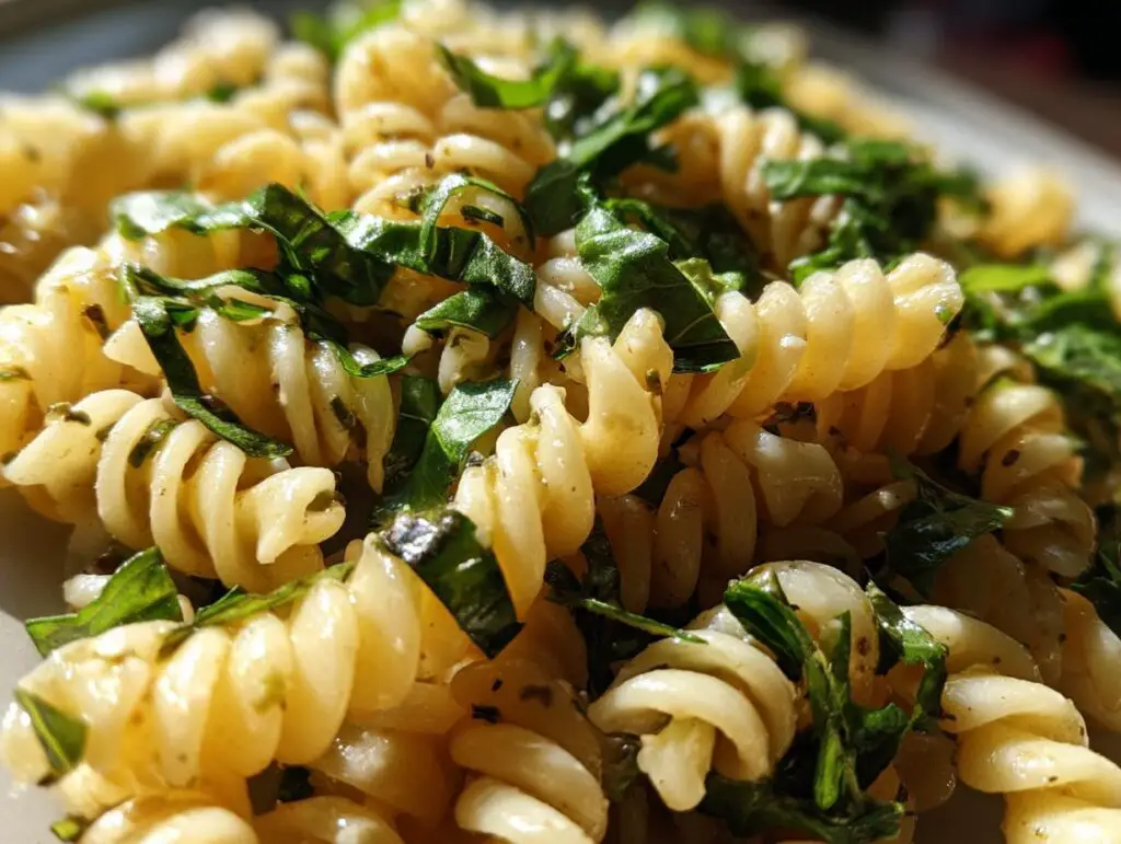 Close-up of pasta salad basil with fusilli pasta and fresh basil leaves.