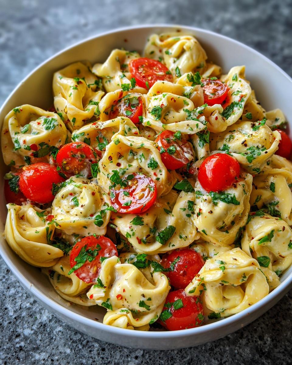 Close-up of pasta salad using cheese tortellini with cherry tomatoes and herbs.