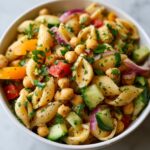 Amazing pasta salad chickpeas in 25 minutes 11 Close-up of a pasta salad chickpeas in a white bowl with vegetables and herbs.