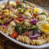 A vibrant pasta salad easter with rotini pasta, vegetables, and hard-boiled eggs.