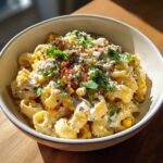 Close-up of a bowl of pasta salad elote, with corn, cheese, bacon, and cilantro.
