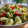 Close-up of a bowl of pasta salad green goddess with tomatoes and herbs. The pasta salad green goddess is a vibrant and fresh dish.