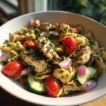 Pasta salad grilled chicken with tomatoes, red onion, and cucumber in a bowl.