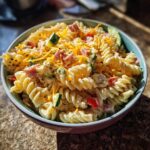 Close-up of a bowl filled with pasta salad kids love, featuring pasta, cheese, ham, and vegetables.