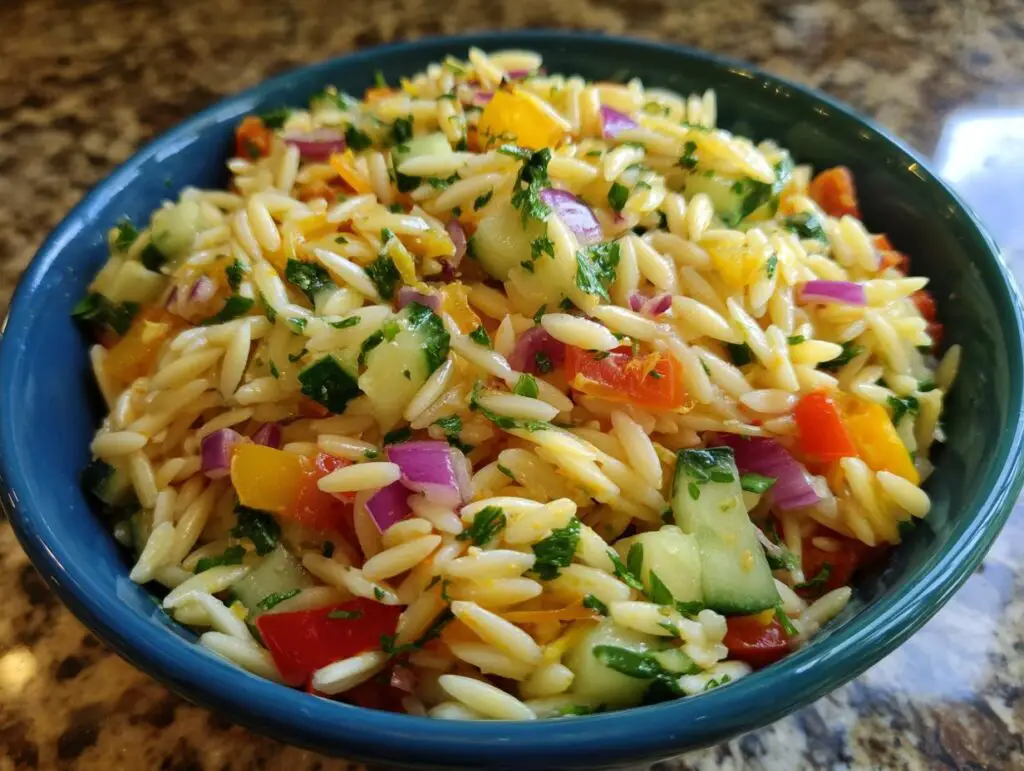 Close-up of a vibrant pasta salad orzo with colorful vegetables in a blue bowl.