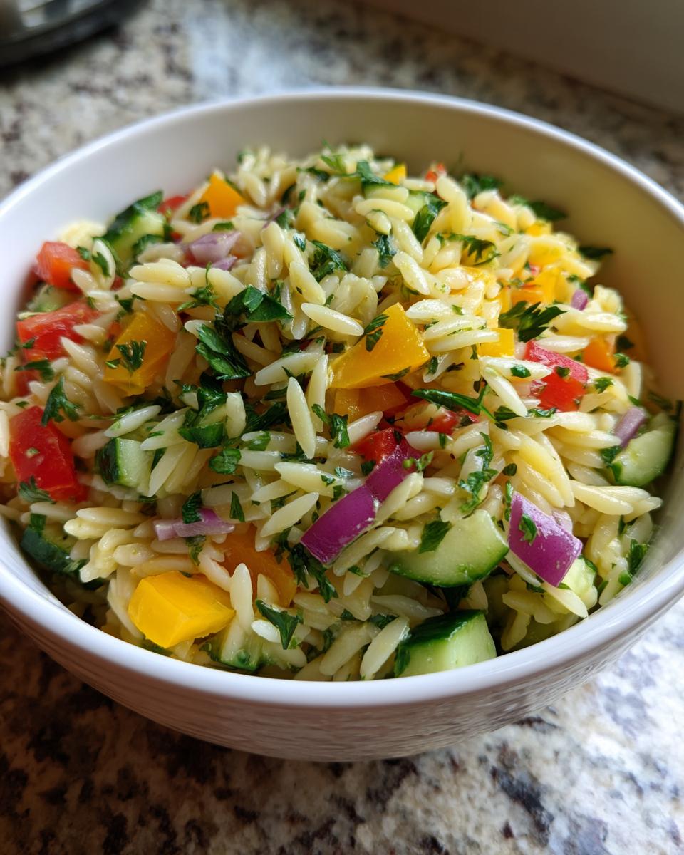 Amazing pasta salad orzo: 30-min delight 8 Close-up of a bowl of pasta salad orzo with colorful vegetables and herbs.