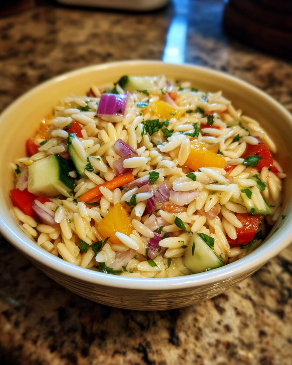 Amazing pasta salad orzo: 30-min delight 10 Close-up of a bowl of pasta salad orzo with colorful vegetables and herbs.