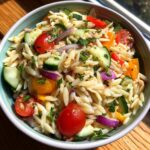 Amazing pasta salad orzo: 25 min summer favorite 11 A vibrant bowl of pasta salad orzo with tomatoes, cucumbers, and red onion.
