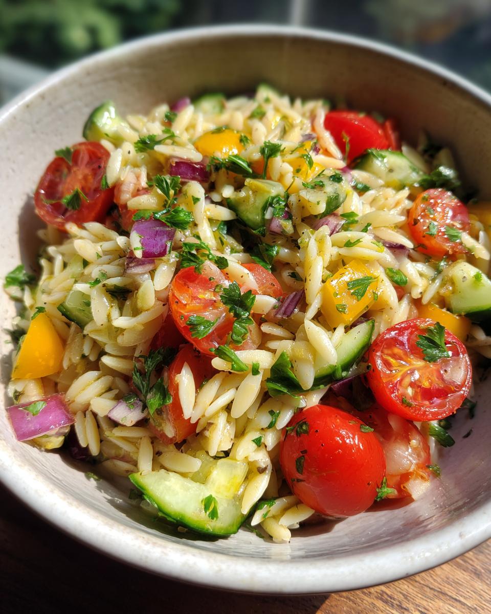 Amazing pasta salad orzo: 25 min summer favorite 9 Close-up of a bowl of pasta salad orzo with cherry tomatoes, cucumber, and herbs.