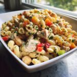 Close-up of a pasta salad protein bowl with chicken, chickpeas, and vegetables.