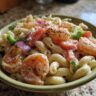 Close-up of a bowl of pasta salad shrimp with macaroni, shrimp, tomatoes, and vegetables.