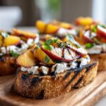 Close-up of Peach Burrata Bruschetta, featuring grilled bread, peaches, burrata, basil, and balsamic glaze.
