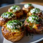 Close-up of crispy Smashed Potatoes with Sour Cream & Chives, garnished with fresh chives.