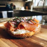 Close-up of a bagel with cream cheese and smoked salmon, part of a Smoked Salmon & Cream Cheese Bagel Board.