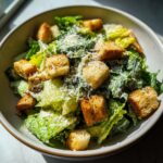 Close-up of a Spring Greens Caesar with homemade croutons, cheese, and dressing.