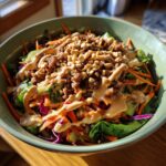 A colorful Spring Roll Bowl with Peanut Sauce, topped with peanuts and drizzled with sauce.